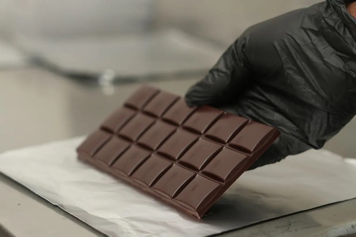 Foto von einer Hand die eine Tafel Schokolade auf ein Stück Alufolie legt - gebana.com