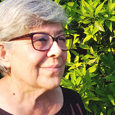 Foto einer griechischen Bäuerin im Seitenprofil, vor einer Hecke - gebana.com