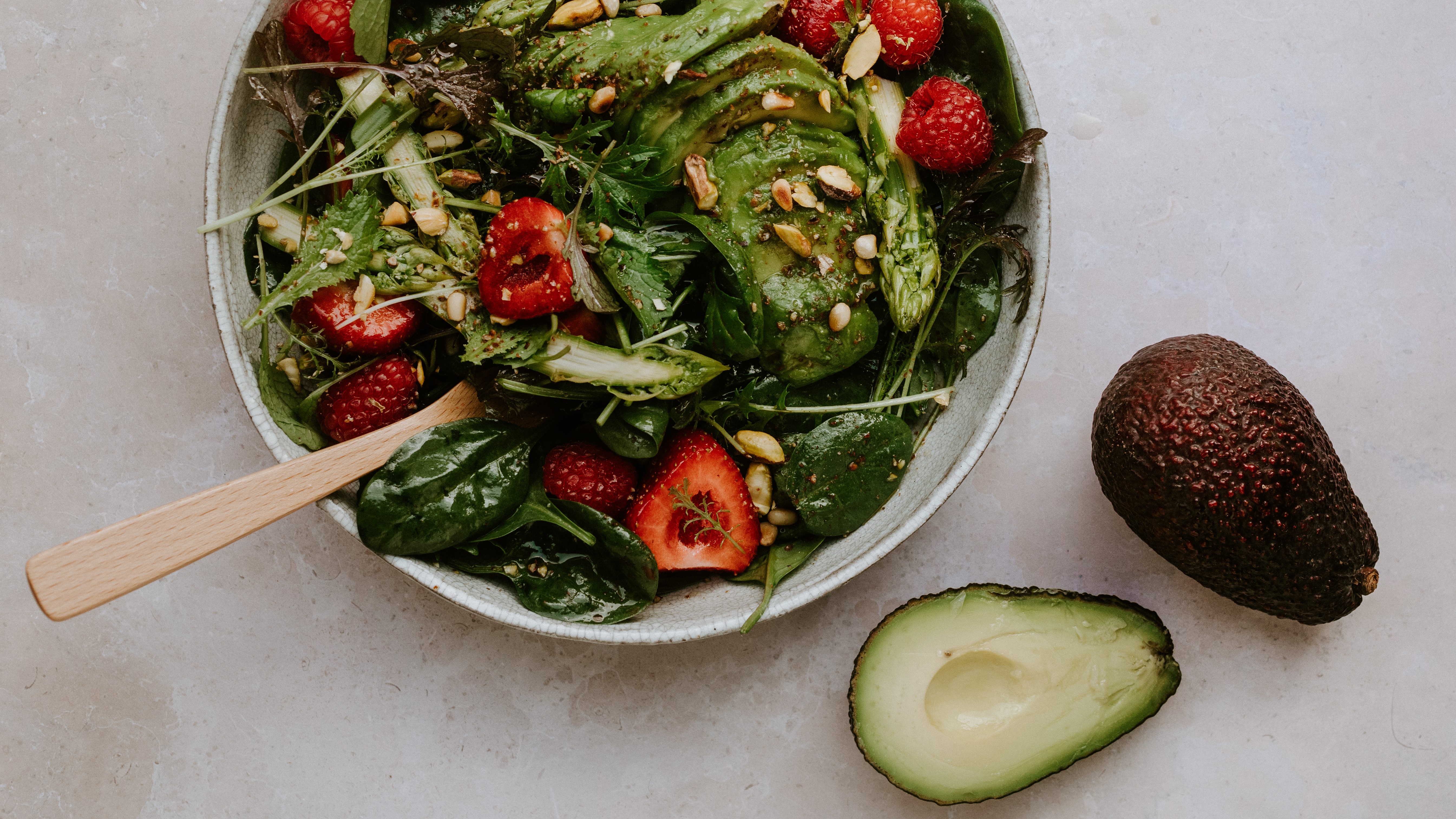 Salade de bébé épinards avec avocat, asperges vertes et fruits rouges
