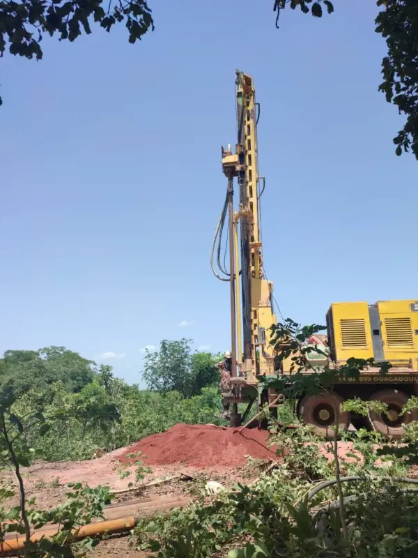 Photo d'un grand engin de chantier jaune forant le trou d'un puits - gebana.com