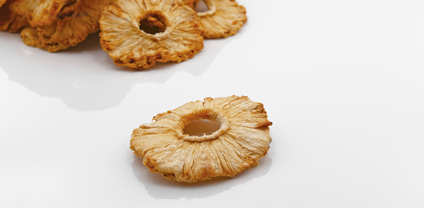 A pile of dried pineapple rings on a white background
